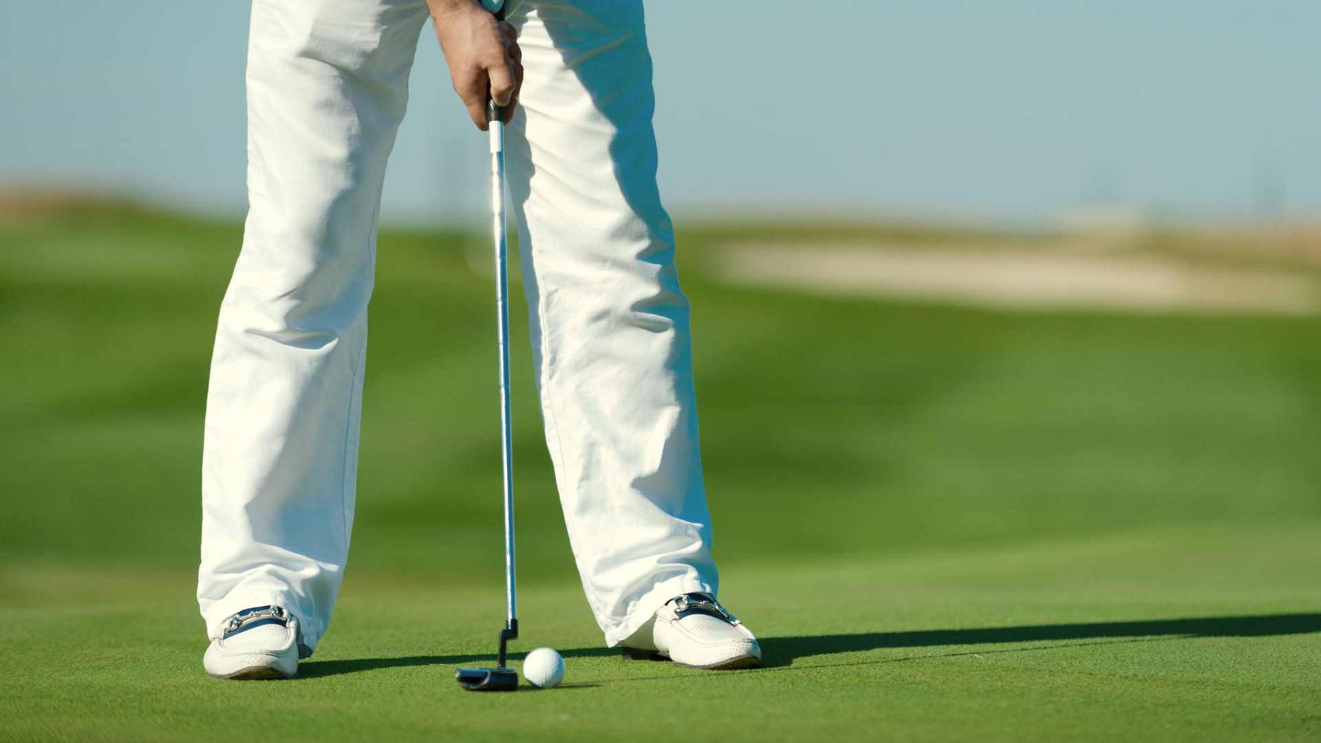 Golfers lower half pictured teeing up to a ball