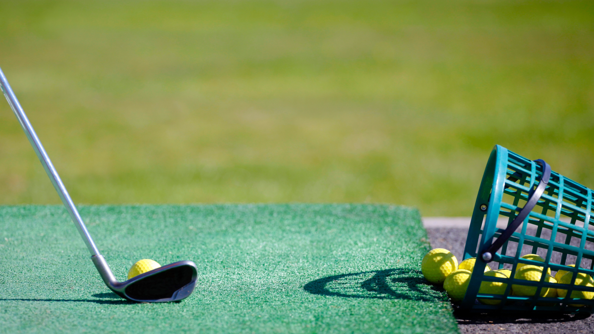 Golf balls in a basket on its side with a club lining up a ball