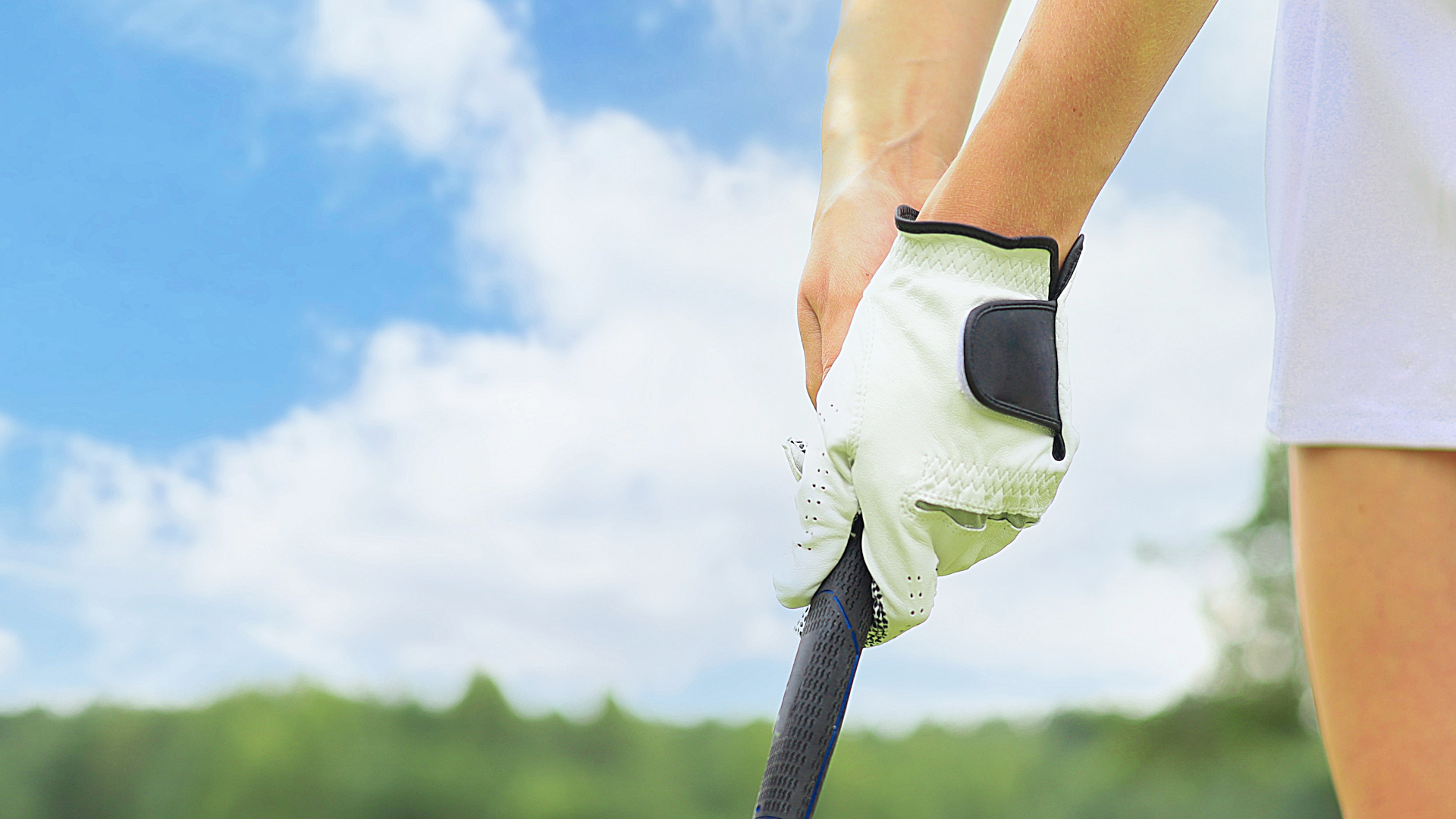 A close up of a woman holding a golf putter with a golf glove on. 