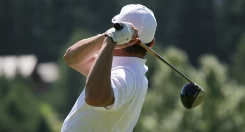 A golfer holding a golf club behind their head and shoulders in the backswing aspect of their golf swing.