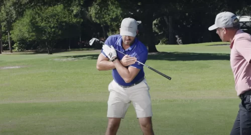 Performance Golf Eric Cogorno holding a golf club across his chest, showcasing the proper shoulder movement of the golf swing.