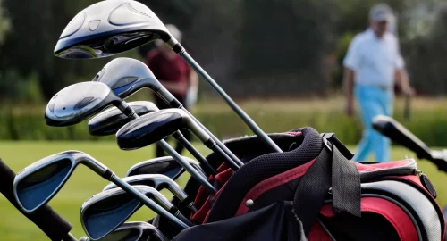 Close up shot of a golf bag with various golf clubs in it.