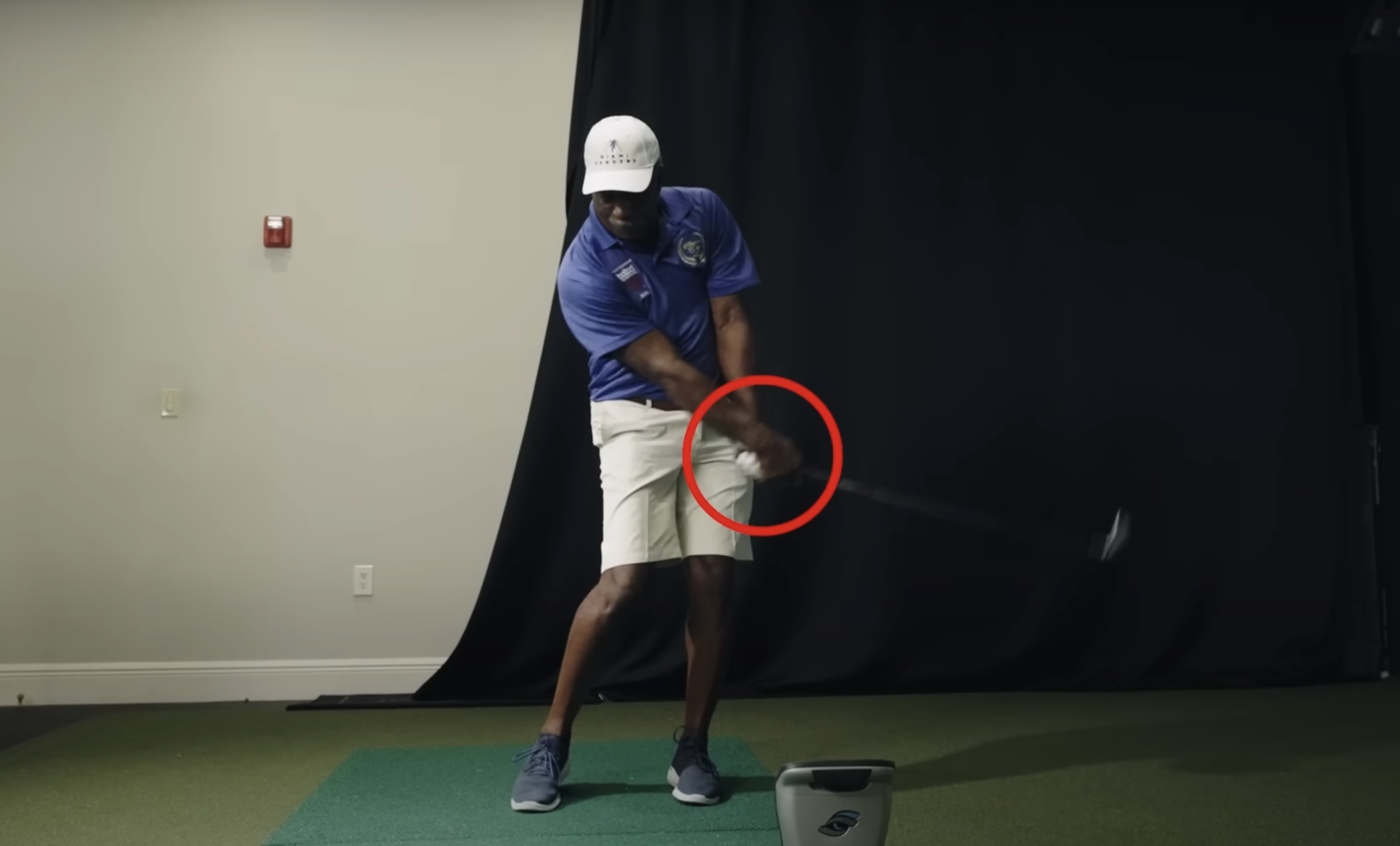 A golf student receiving feedback on their golf swing, with a red circle emphasizing an incorrect hand position when gripping the golf club.