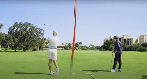 Performance Golf coaches Eric Cogorno and Rick Smith looking at a successfully hit golf ball with the trajectory shown in a red line.